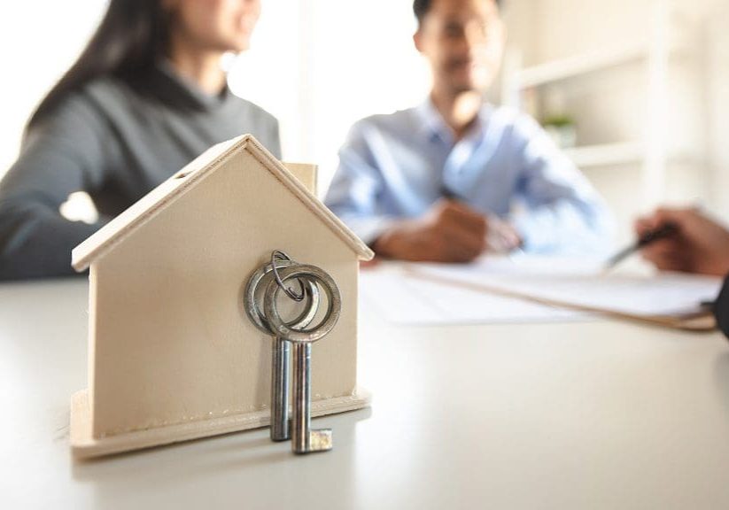 Close-up shots of the model house and keys with groups of people are made of real estate purchase contract is in the background. Close-up shots of the model house and keys with groups of people are made of real estate purchase contract is in the background.