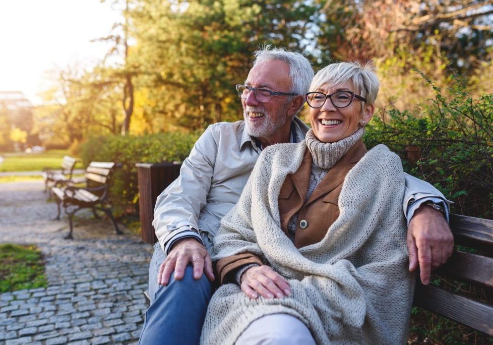 Smiling senior couple sitting on the bench in the park together
